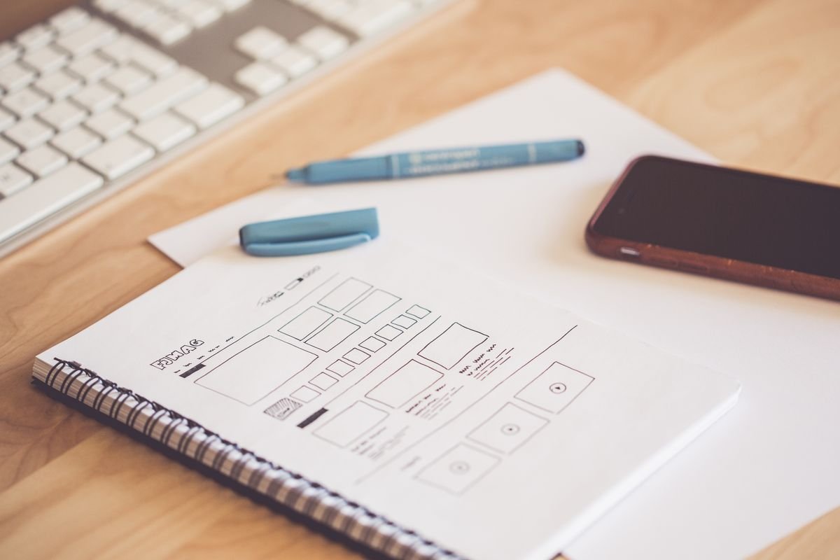 Croquis de maquette de site web, smartphone et clavier sur un bureau