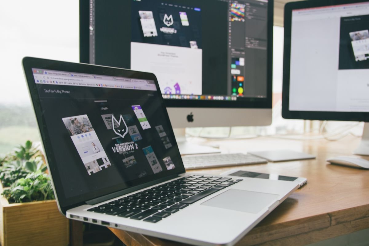 Poste de travail avec ordinateur portable et écrans affichant un logiciel de design