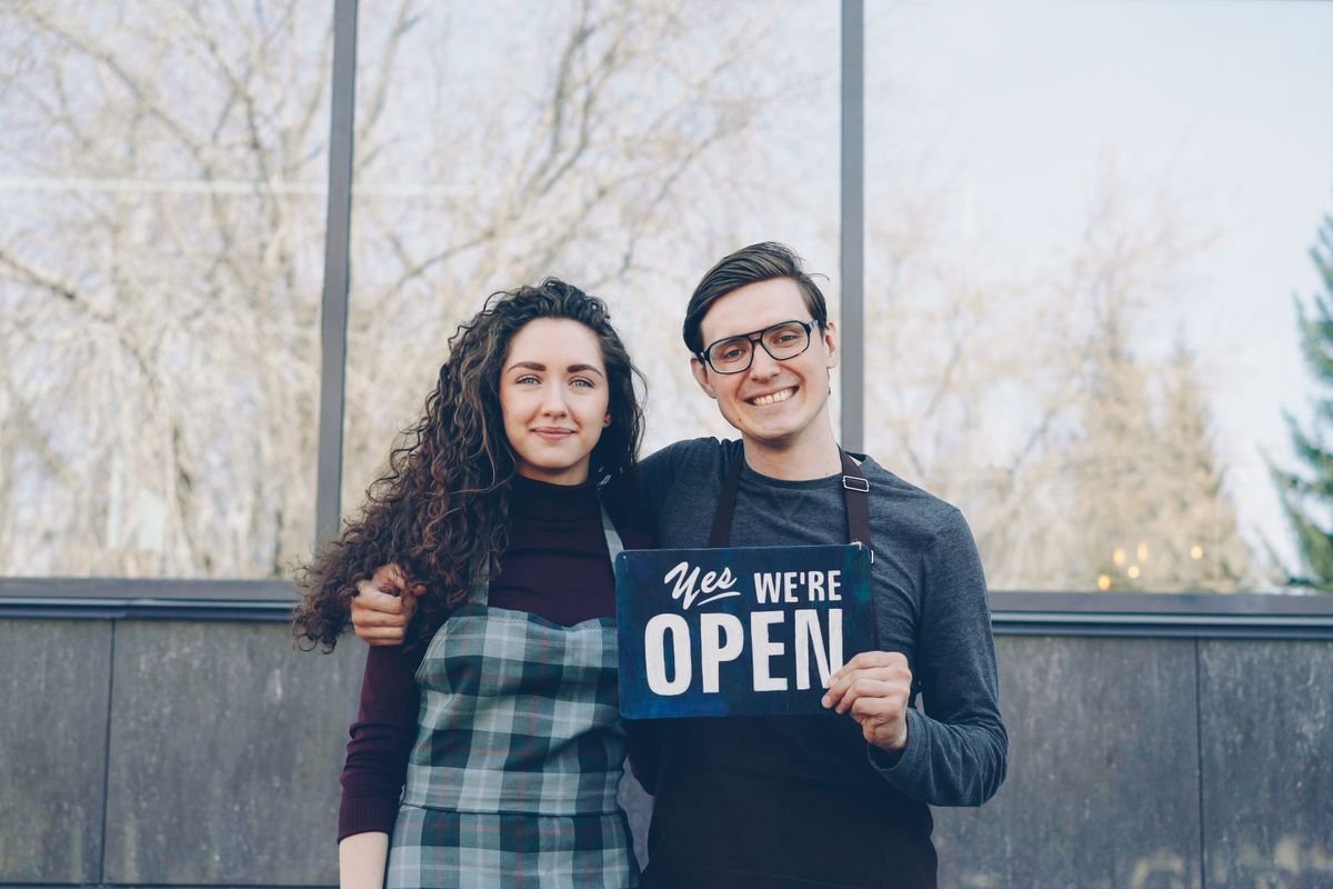 Dirigeants de petite entreprise accueillant leurs clients devant leur commerce