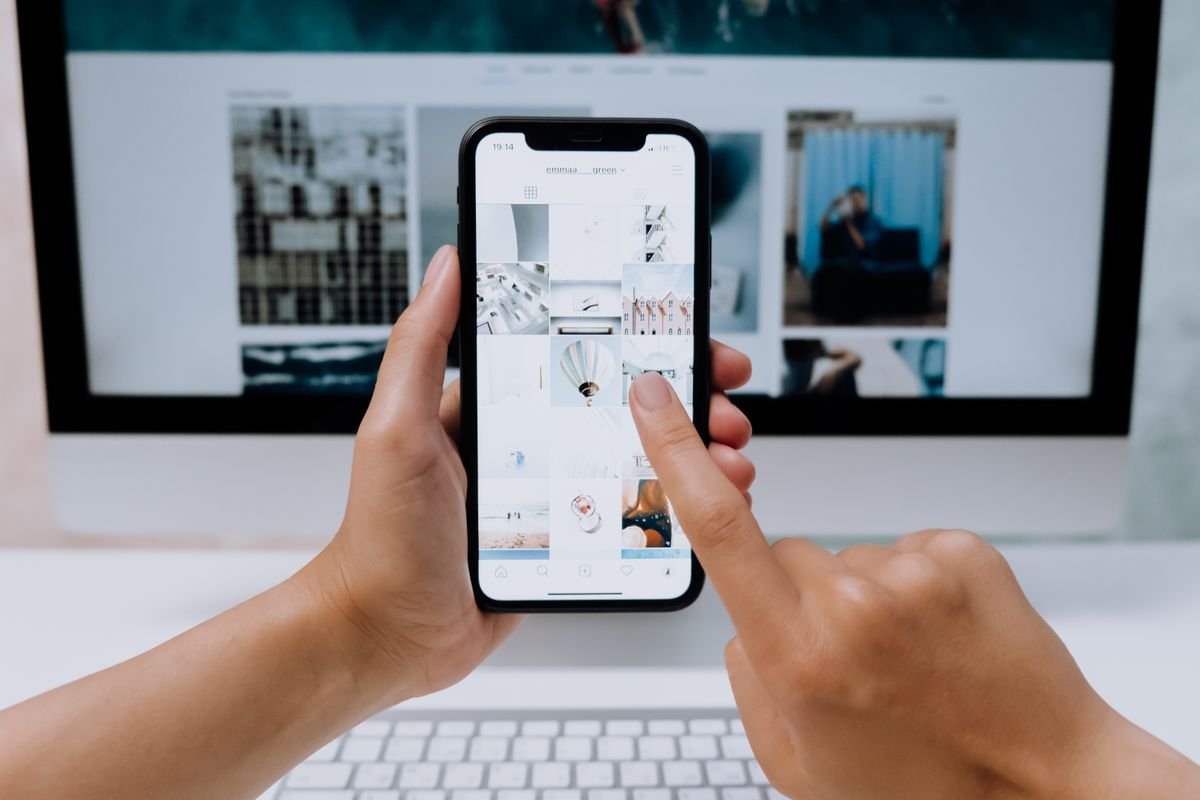 Personne consultant un site web sur smartphone devant un ordinateur de bureau
