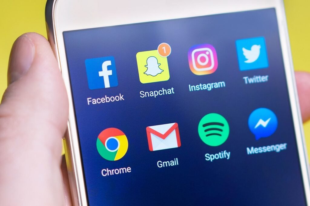 Main tenant un smartphone affichant des applications de réseaux sociaux