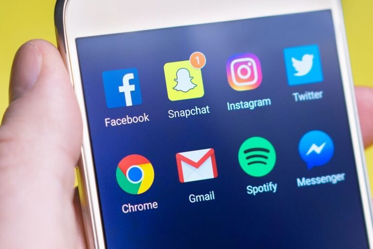 Main tenant un smartphone affichant des applications de réseaux sociaux