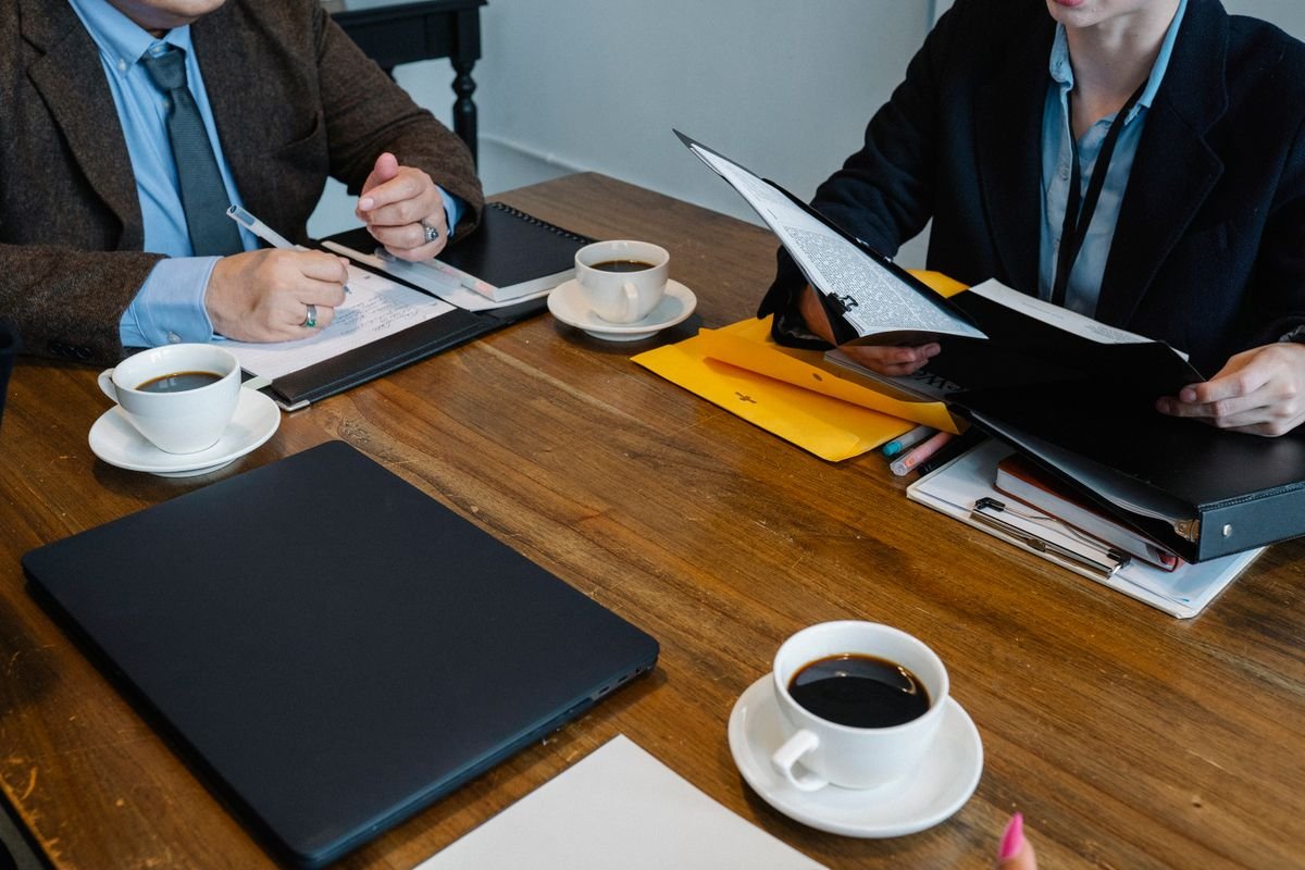 Deux personnes comparant des documents autour d'une table de travail