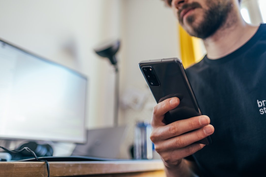 Homme consultant un site internet sur son smartphone avant de contacter un professionnel