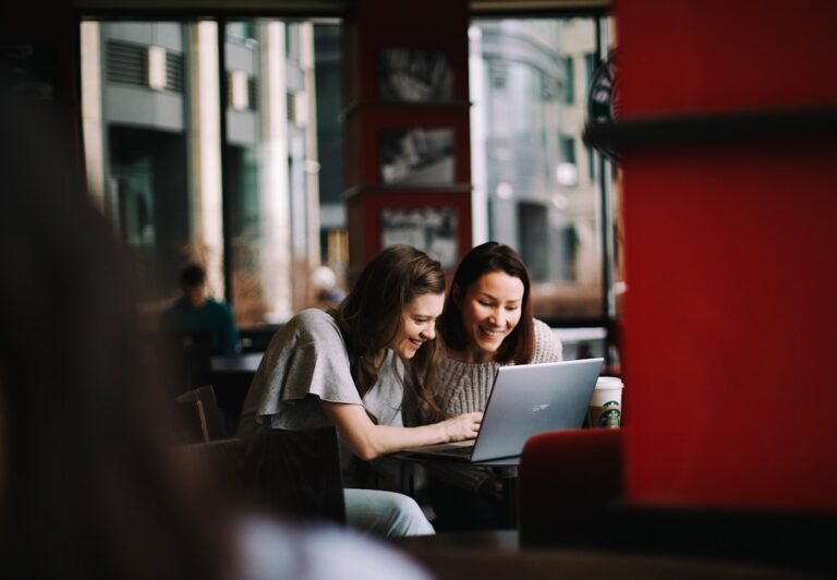 Une indépendante présente son travail à une cliente sur un ordinateur portable dans un café
