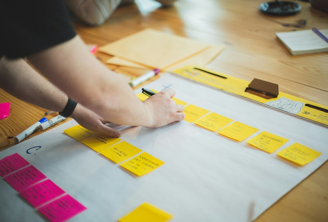 Main qui rédige une stratégie marketing sur une feuille posée sur un bureau