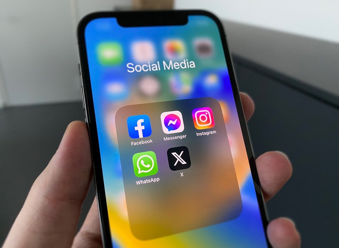 Main tenant un smartphone affichant les icônes des principaux réseaux sociaux