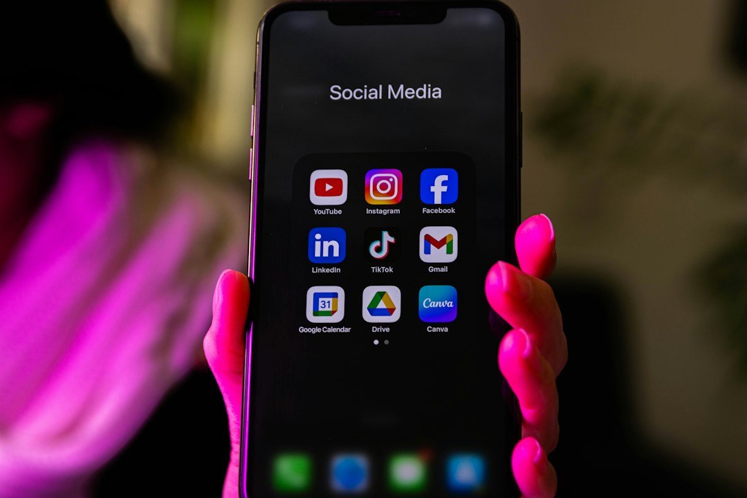 Smartphone tenu en main affichant un dossier d’applications de réseaux sociaux